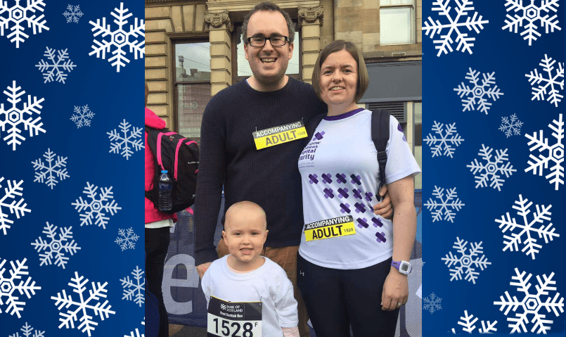 Emily and her Mum and Dad stand at the beginning of the Great Scottish Run. All three are wearing race numbers.