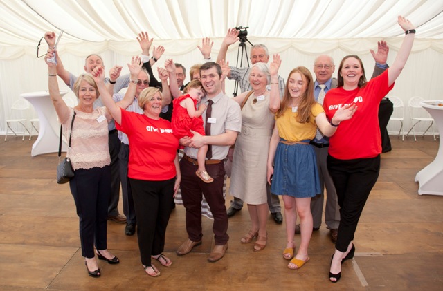 Group photo of toddler Skye Edwards with Dad Craig. Staff members and donors cheer alongside. 