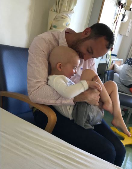 Keith cuddles Edie while she sits on his knee laughing. 