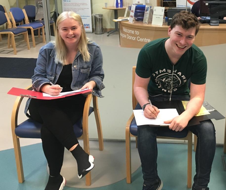 Students sitting and smiling while completing their personal detail forms. 