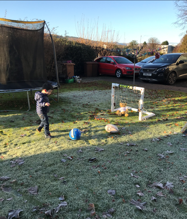 Iain plays football outside in the garden.  