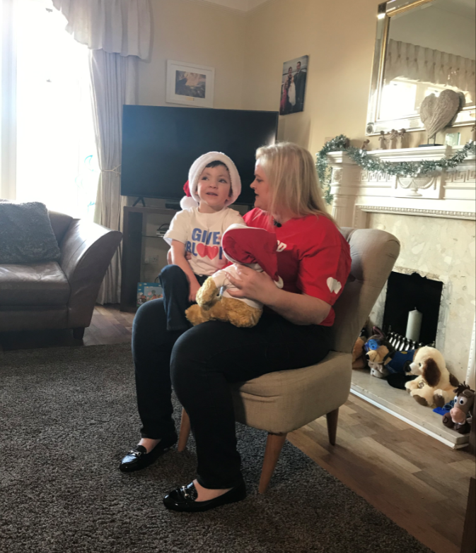 Iain sits on Mum Nicola's knee. Both are wearing Give Blood t-shirts. 