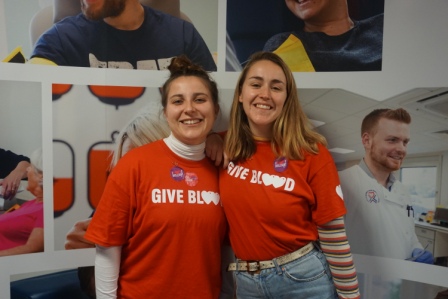 Martha and Hanna smiling wearing 'give blood' t-shirts and 'Give Blood 4 Good' stickers