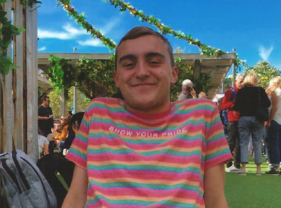 Patrick smiling sitting outside on a sunny day